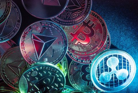 Horizontal view of cryptocurrency tokens, including Bitcoin, dogecoin, and ethererum seen from above on a black background. High quality photo